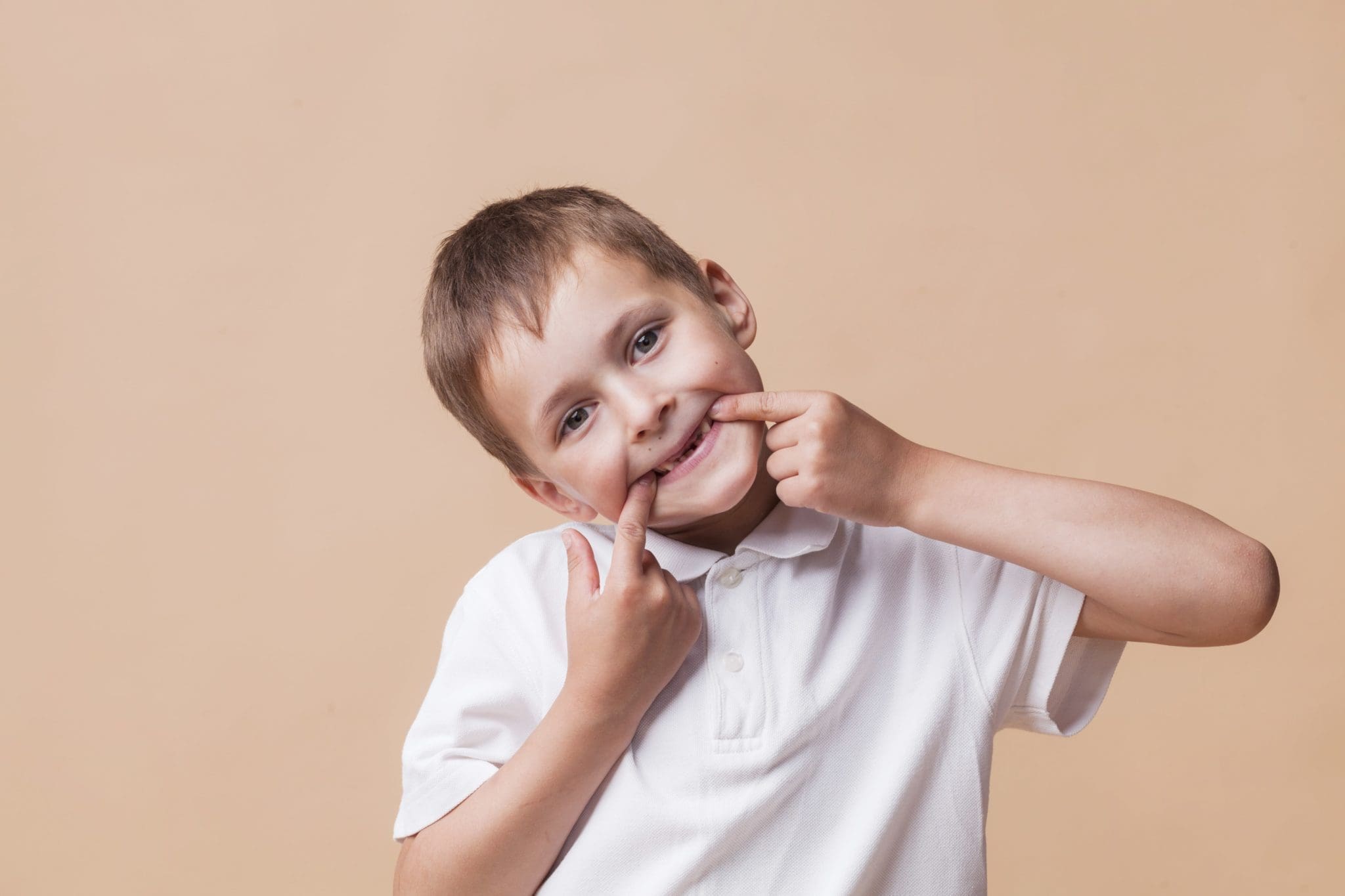 portrait-little-boy-looking-camera-teasing-beige-background-min-scaled